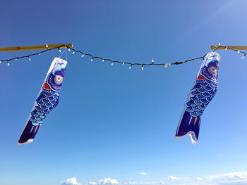 Low angle view of decoration hanging against blue sky