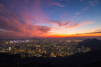 Illuminated cityscape against sky during sunset