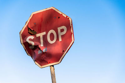 Low angle view of road sign against blue sky