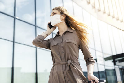 Young woman using mobile phone while standing on mirror