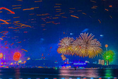 Firework display against blue sky at night