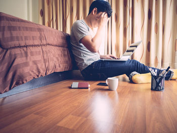 Work from home concept. man working on laptop computer sitting on the floor in bedroom.