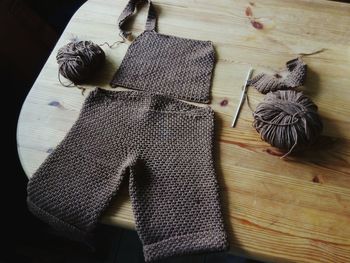 High angle view of incomplete sweater with crochet hook and wool on table