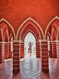 Rear view of woman standing against tiled wall