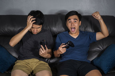 Young man using mobile phone while sitting on sofa at home