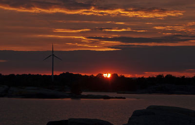 Lake with wind turbine against sunset