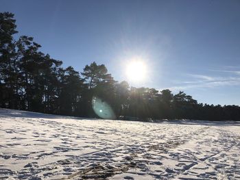 Scenic view of snow covered land against bright sun
