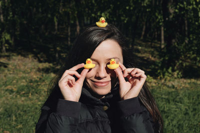 Close-up of young woman with rubber ducks on field