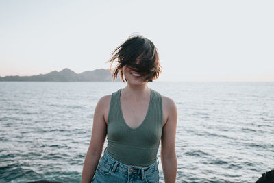 Rear view of young woman standing against sea