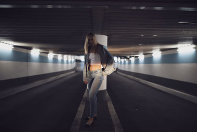 Portrait of serious woman standing under illuminated tunnel