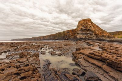 Rock formations on landscape against cloudy sky