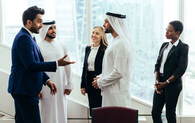 Smiling colleagues looking at businessmen discussing in meeting at office