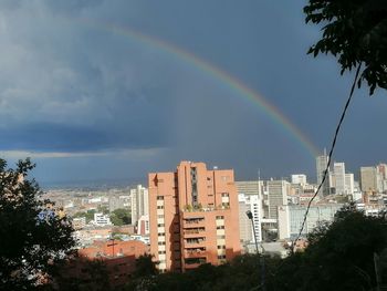 Rainbow over buildings in city against sky