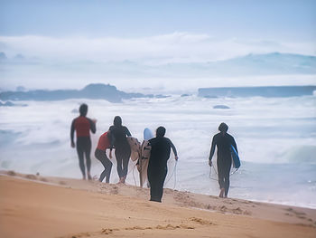 Rear view of people walking on beach