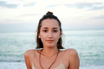 Portrait of beautiful young woman at beach against sky