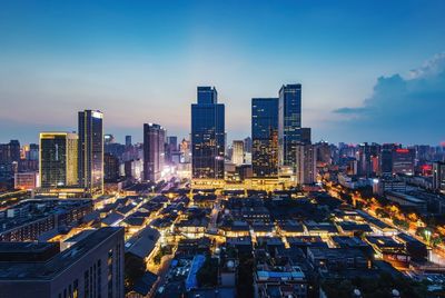 High angle view of illuminated buildings in city against sky at dusk