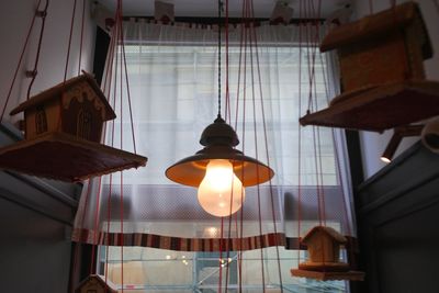 Low angle view of illuminated light bulb hanging from ceiling