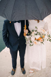 Midsection of man holding flower bouquet