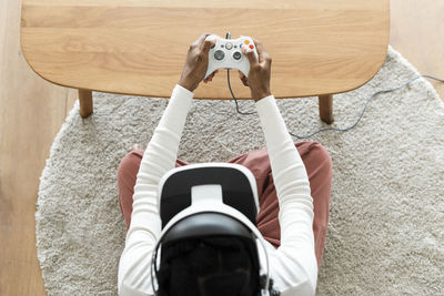 Directly above shot of man paying video game by table
