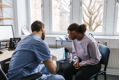 Male doctor discussing reports with female patient during visit at hospital