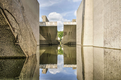 Large concrete hydrolic test facility, no longer in use, reflecting in the surrounding canal