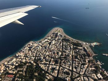 Cropped image of airplane flying over townscape and sea