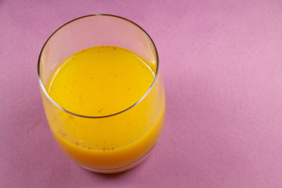 High angle view of yellow drink against pink background