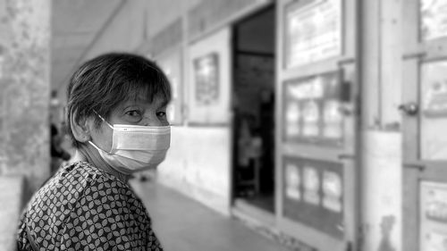 Portrait of senior woman wearing mask sitting at corridor