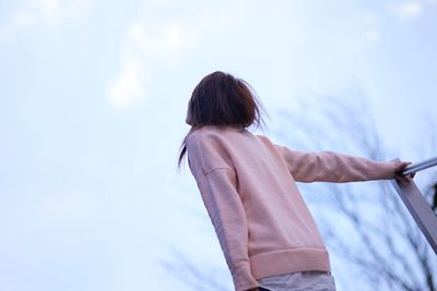 Rear view of woman standing against sky