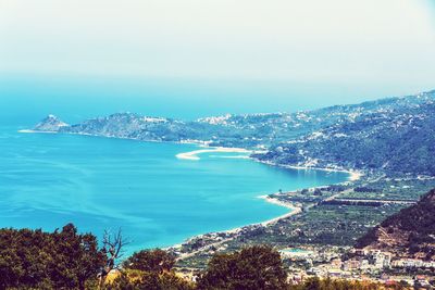 Aerial view of city by sea against sky