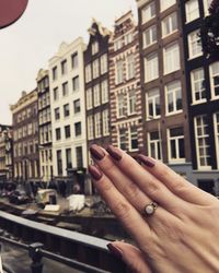 Close-up of hand against buildings in city