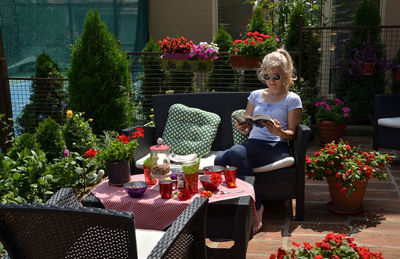 Woman reading a book by a set table in a lush garden