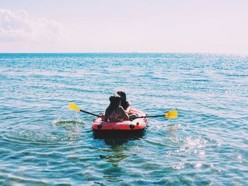 People boating in sea against sky