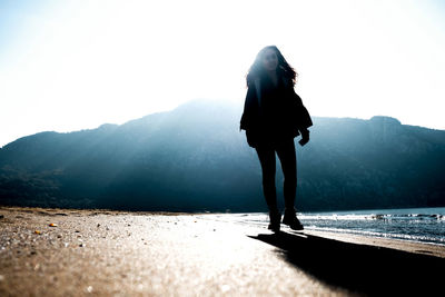 Rear view of woman standing on mountain against sky