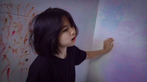 Woman looking away by blood on wall