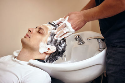 Close-up of man washing hands in bathroom