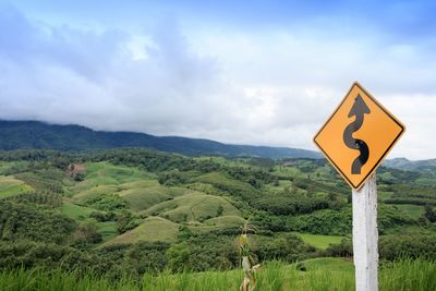 Road sign by mountains against sky