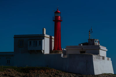 Low angle view of lighthouse by building against sky