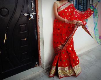 Midsection of woman standing by red umbrella