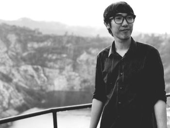 Portrait of young man standing against mountains