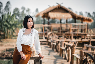 Woman looking away while leaning against railing on footbridge