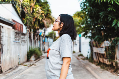 Side view of young woman looking away while standing outdoors