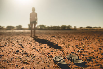 Close-up of flip-flops against boy standing on field