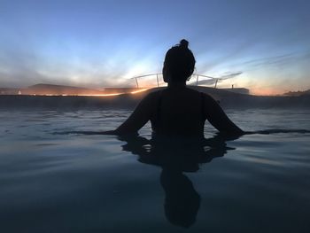 Rear view of silhouette man standing at beach during sunset