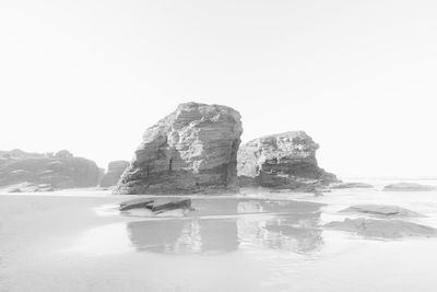 Rock formation in sea against clear sky