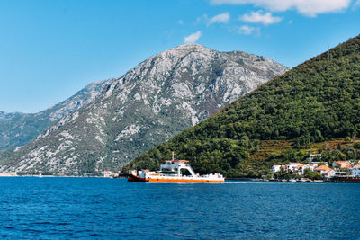 Boat sailing on river by mountains against clear blue sky