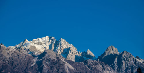 Low angle view of rocky mountains against blue sky
