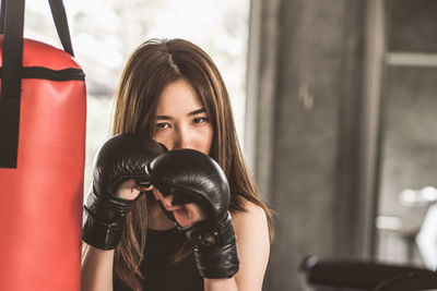 Portrait of confident young woman punching bag in gym