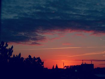 Silhouette trees against dramatic sky during sunset