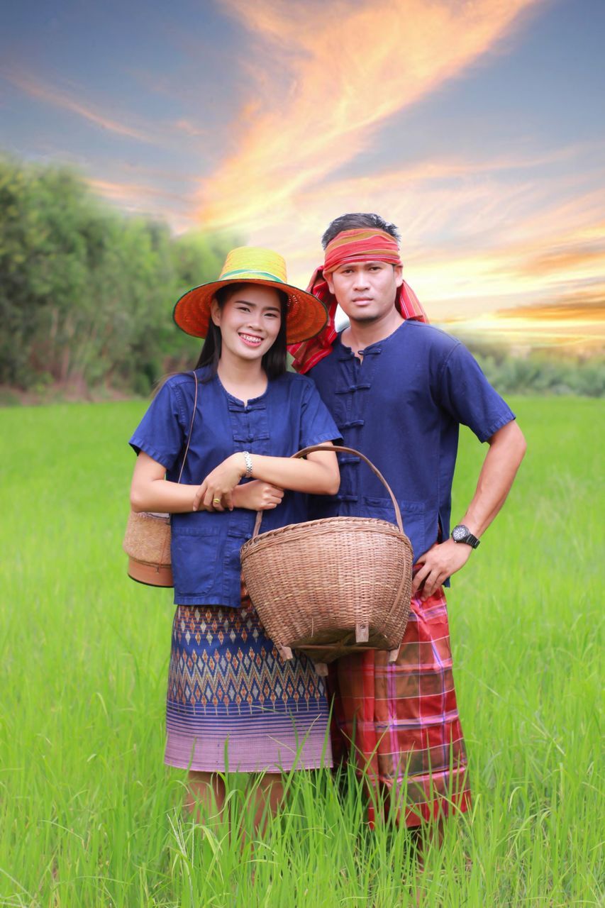 two people, togetherness, looking at camera, standing, smiling, adult, portrait, men, emotion, holding, young adult, happiness, front view, nature, cap, grass, agriculture, food, rural scene, farmer, baseball cap, outdoors, teamwork